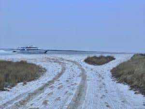 a boat in the ocean and snow on the beach 