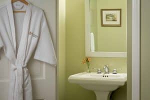 a bathroom with a sink, a picture hanging and a bathrobe on the white door