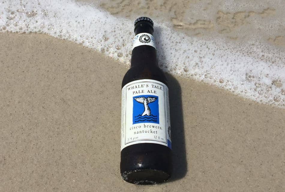 Close up view of Whale Tale Pale Ale beer bottle on top of sand