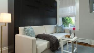 White upholstered sofa with dark wooden cabinetry behind, small white coffee table, and window