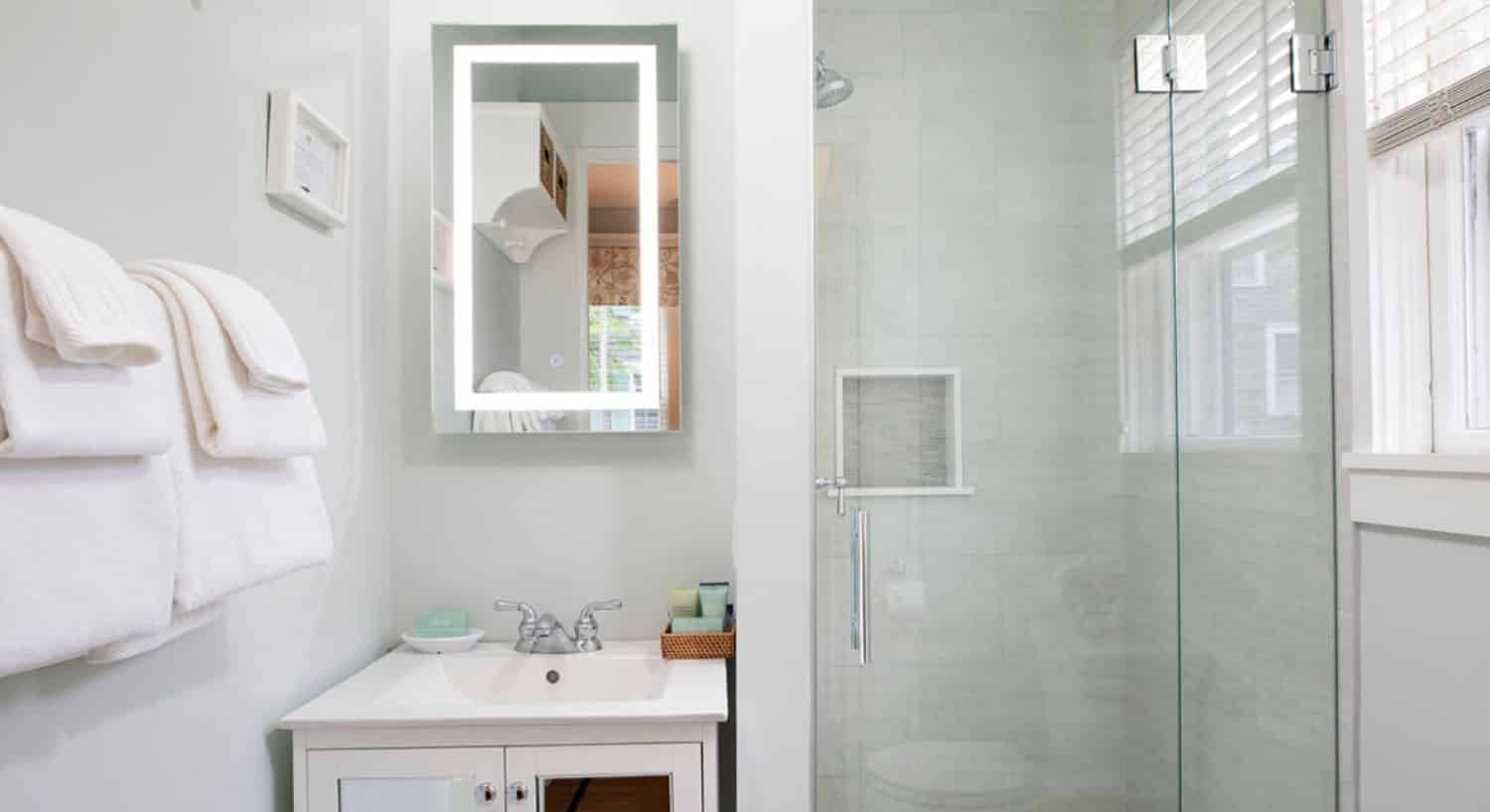 Bathroom with white vanity, medicine cabinet with mirrored front, and tiled shower with glass door